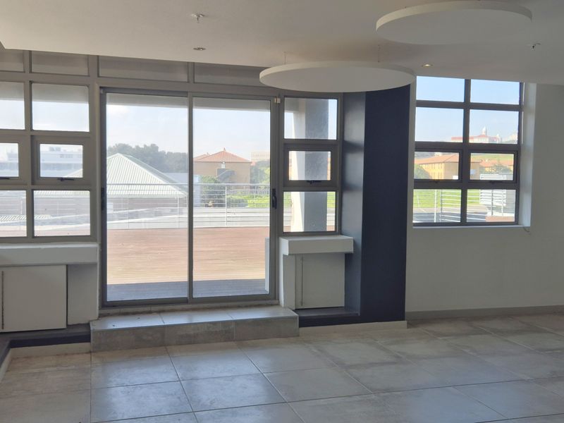 Modern office space featuring large windows, tiled flooring, built-in cabinetry, and direct access to an outdoor balcony area.