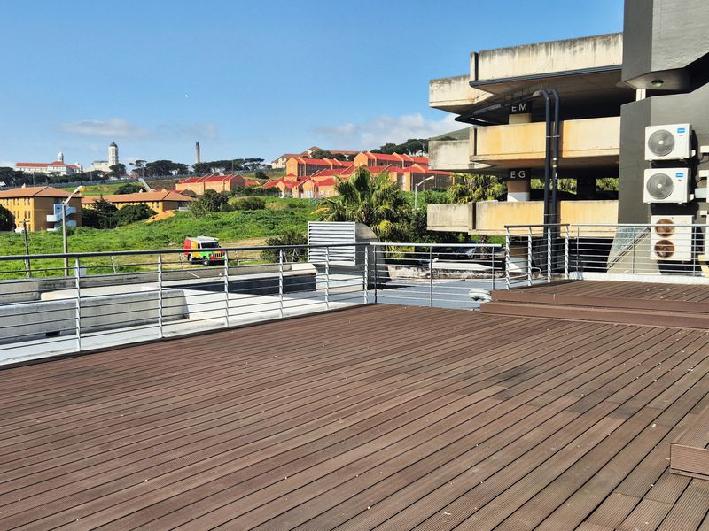 Spacious outdoor terrace featuring composite decking, stainless steel railing, and multiple wall-mounted air conditioning units with an expansive urban view.
