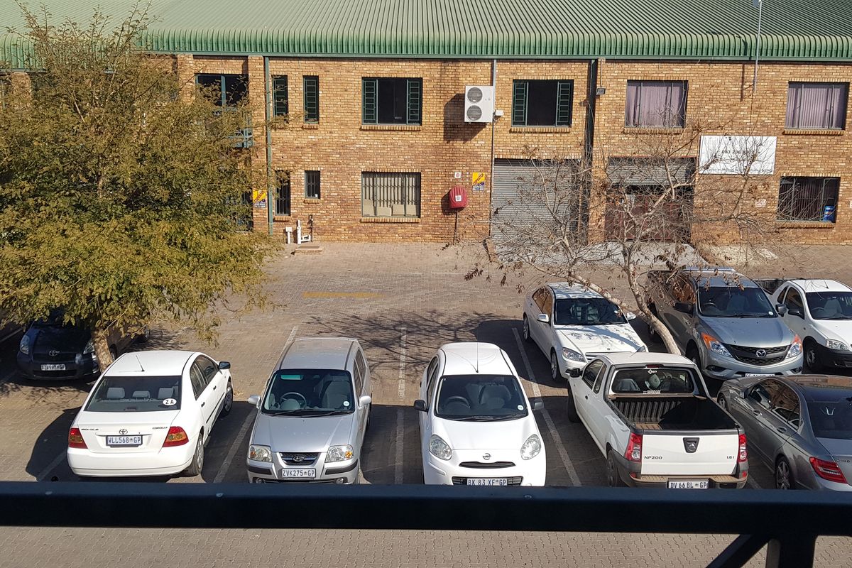 Exterior view of an industrial complex featuring face-brick facade, metal roofing, and a paved parking area with multiple vehicle bays.