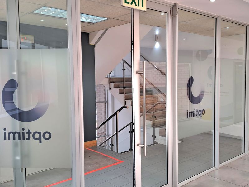 Modern office entrance featuring glass partition walls, aluminium framing, and a staircase with stainless steel handrails, providing a professional and bright reception area.