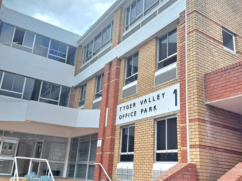 Exterior view of the Tyger Valley Office Park building, featuring a multi-story brick facade with aluminum windows and a paved entrance staircase.