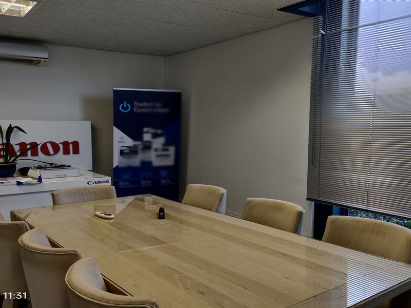 A functional office meeting room featuring a suspended ceiling, recessed lighting, split-system air conditioning, and venetian blinds for light control.