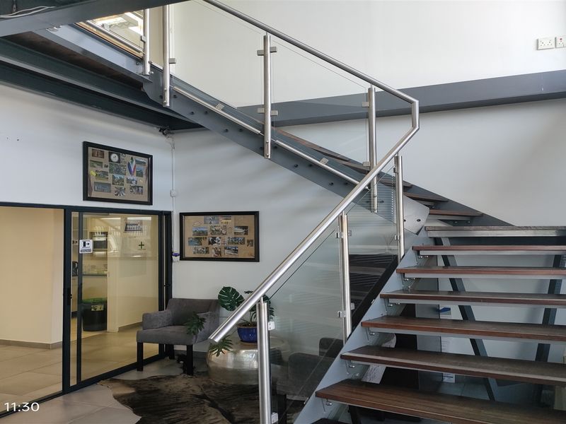 Modern industrial-style entrance featuring a striking steel staircase with timber treads and a glass balustrade, leading to an upper level.