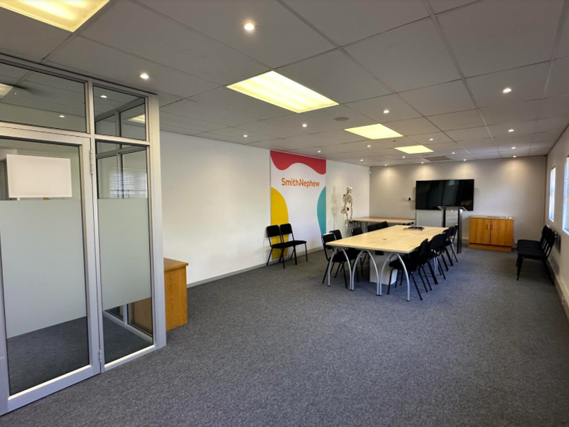 A professional office space featuring suspended ceilings, recessed lighting, carpeted flooring, and aluminium-framed glass partitioning, suitable for a corporate meeting or workspace environment.