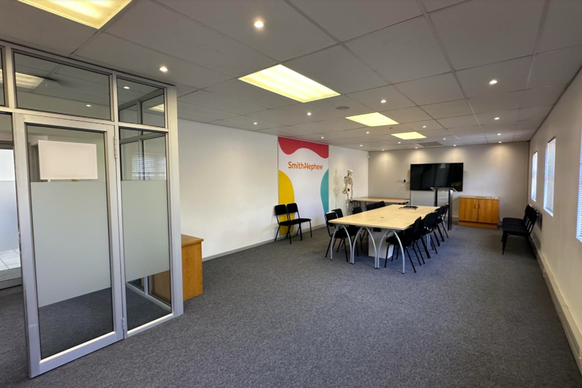 A professional office space featuring suspended ceilings, recessed lighting, carpeted flooring, and aluminium-framed glass partitioning, suitable for a corporate meeting or workspace environment.