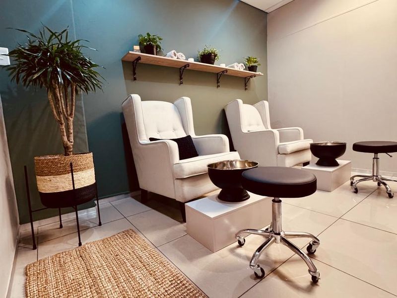 A well-maintained commercial space featuring tiled flooring, recessed ceiling lighting, and wall-mounted shelving, currently configured for salon or spa services.