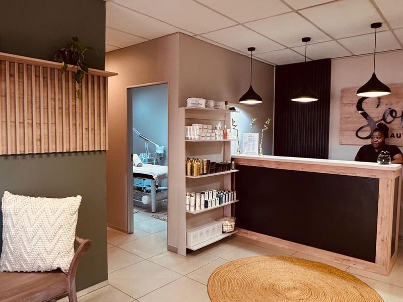 A professional retail reception area featuring a built-in service counter, modern pendant lighting, slatted wood wall accents, and clean tiled flooring.