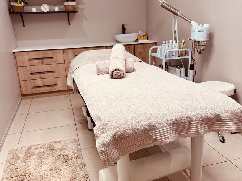 A well-maintained treatment room featuring built-in cabinetry, a vessel sink, and wall-mounted shelving, suitable for professional beauty or wellness services.