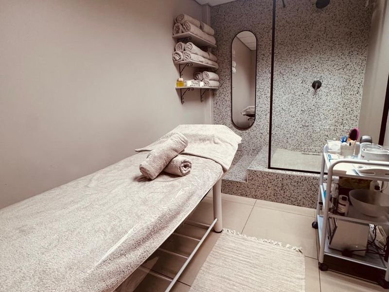 A well-maintained treatment room featuring a walk-in shower with modern terrazzo-style tiling, recessed lighting, and neutral floor tiles.