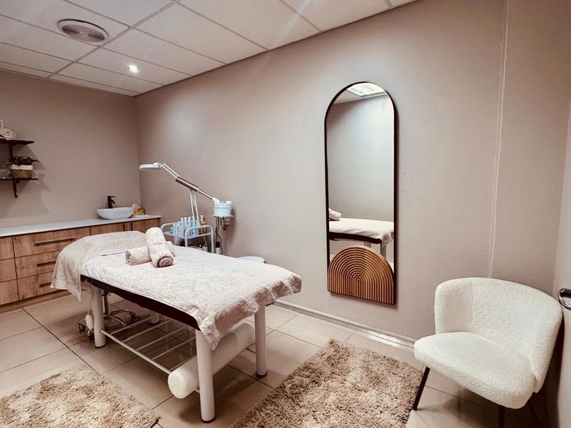 A well-maintained treatment room featuring a built-in vanity with sink, tiled flooring, and professional recessed lighting, suitable for beauty or clinical services.
