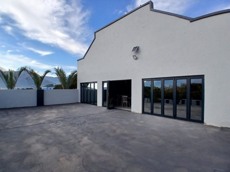 Spacious outdoor patio area featuring modern dark-framed bi-fold doors, concrete flooring, and a solar-powered security light, ideal for outdoor entertaining.