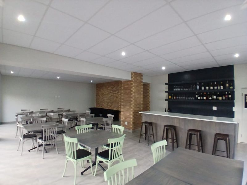 A spacious bar area featuring a built-in counter, fixed shelving, and an exposed brick feature pillar, suitable for guest house entertainment.