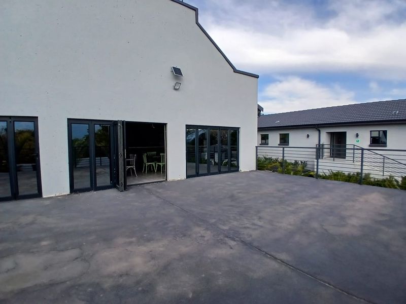 Spacious outdoor patio area featuring concrete flooring, modern bi-fold doors, and metal safety railings, providing a seamless transition to the interior space.