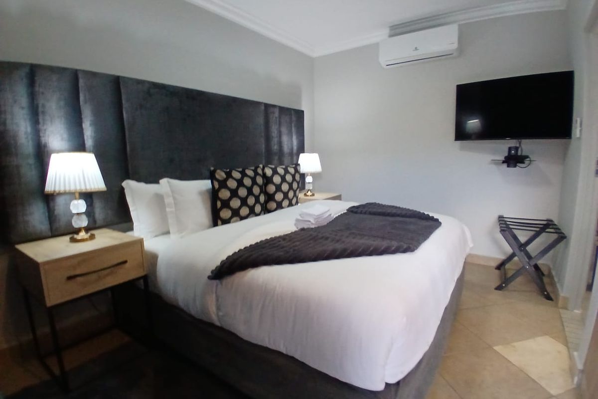 A well-maintained bedroom featuring tiled flooring, a wall-mounted television, and an integrated air conditioning unit for climate control.