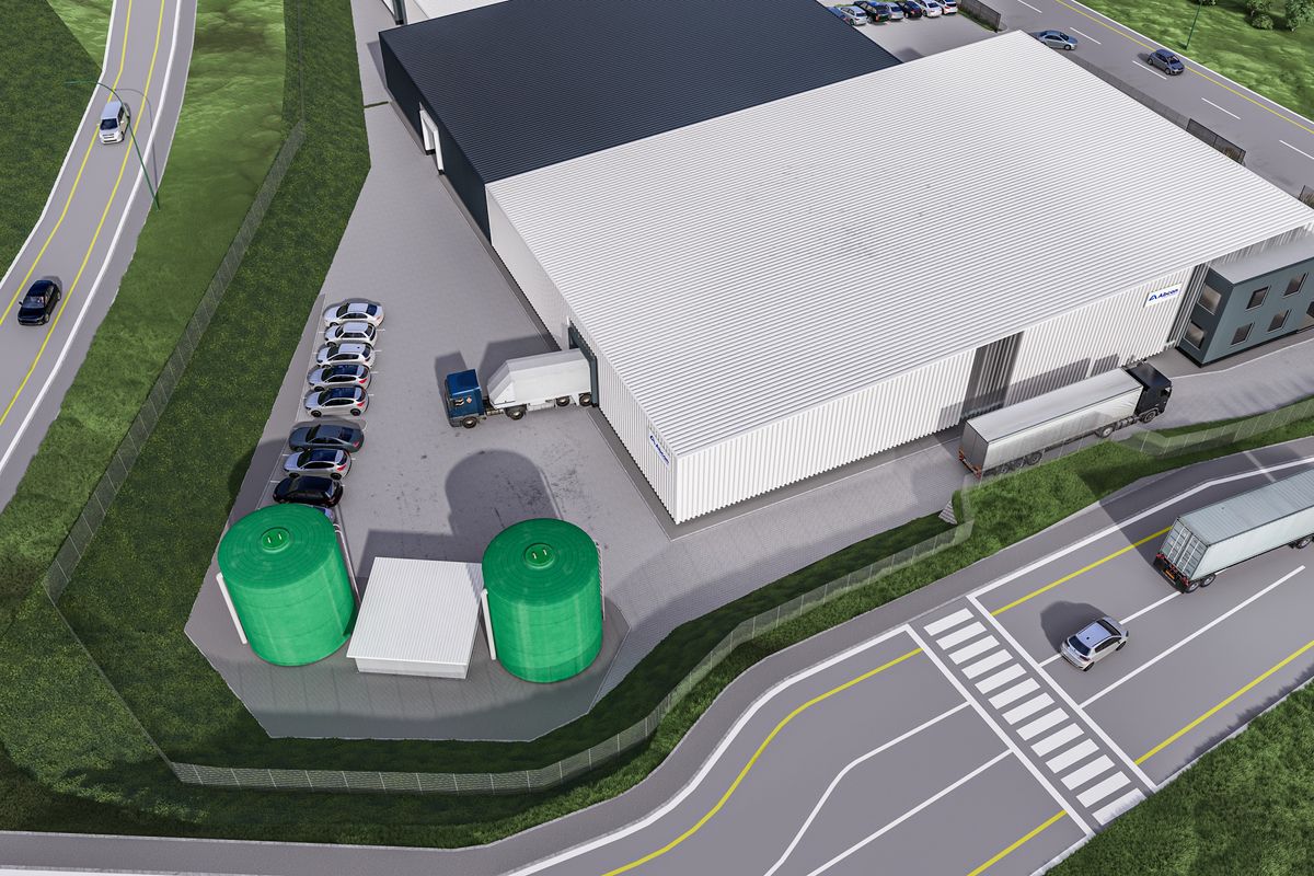 Aerial view of an industrial warehouse facility featuring large loading bays, paved parking areas, and external water storage tanks.