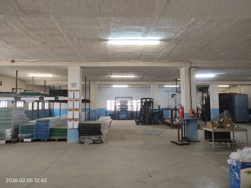Spacious industrial utility area featuring concrete flooring, exposed ceiling structure, and functional fluorescent lighting, suitable for storage or manufacturing operations.