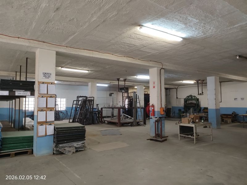 Spacious industrial utility area featuring concrete flooring, exposed ceiling, and structural support columns, suitable for manufacturing or storage operations.