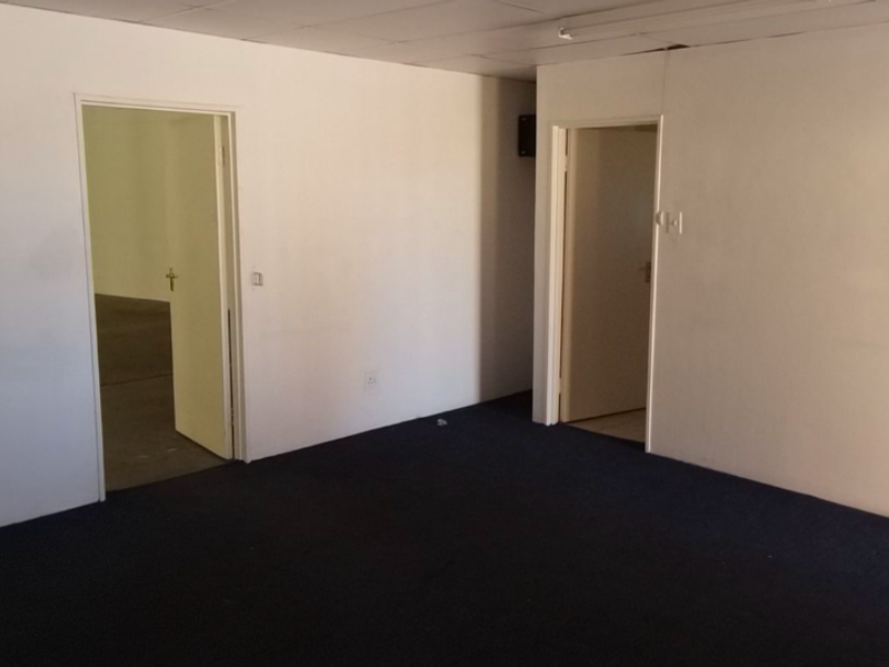 An empty office space featuring dark carpeting, white walls, and a suspended ceiling, providing a blank canvas for commercial use.
