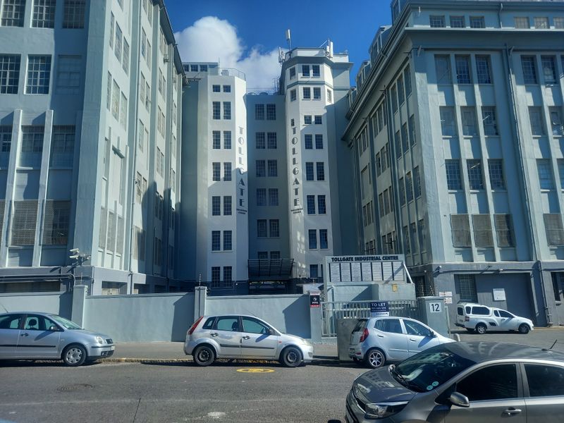 Front elevation of the Tollgate Industrial Centre, featuring a multi-story industrial building with secure perimeter fencing and gated access.