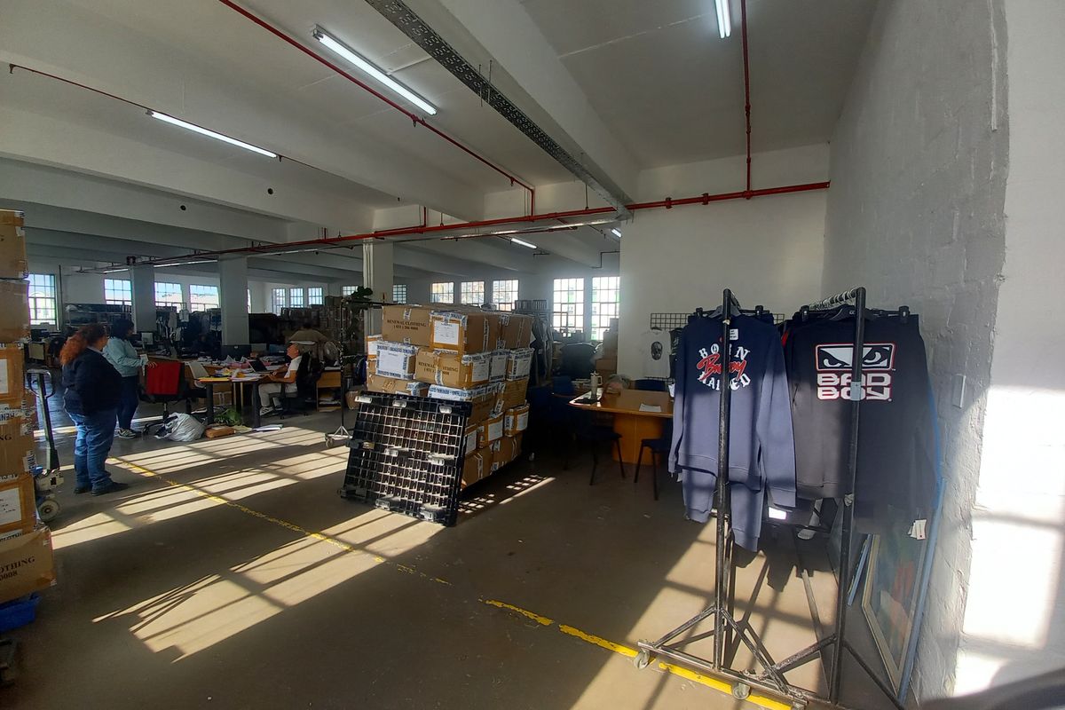 Spacious industrial utility area featuring exposed fire sprinkler systems, high ceilings with fluorescent lighting, and durable concrete flooring suitable for warehouse or workshop operations.