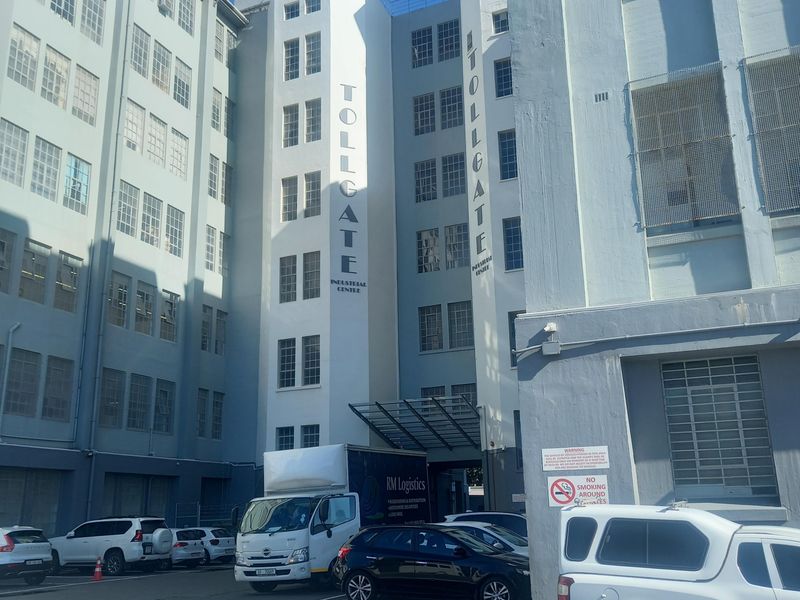 Exterior view of the Tollgate Industrial Centre, featuring a multi-story facade with industrial windows and an adjacent paved parking area.