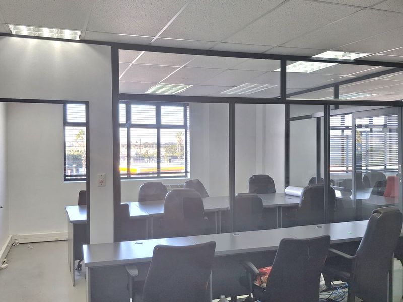 A professional office space featuring glass partition walls, suspended acoustic ceiling tiles, and integrated desk workstations.