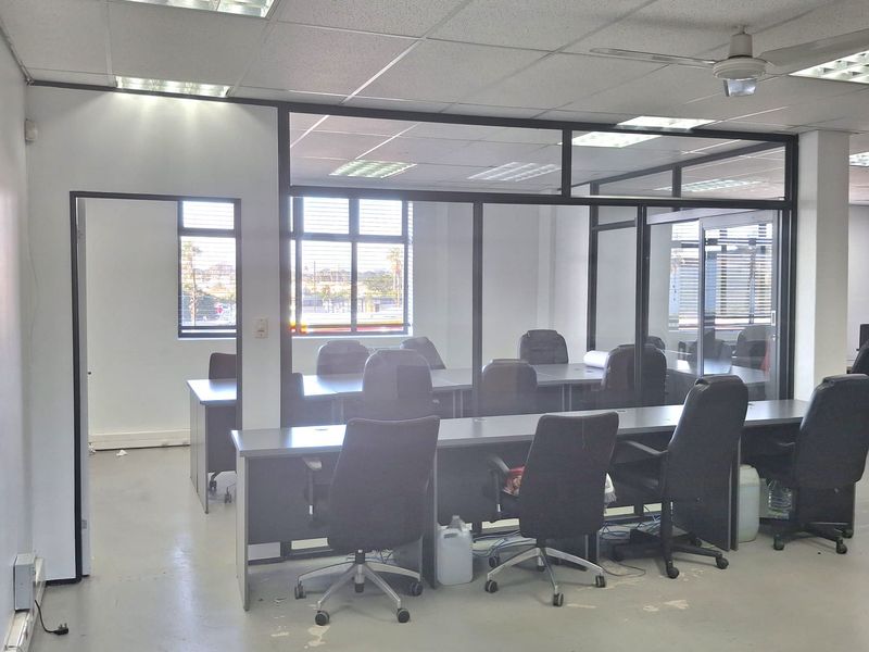 A functional office space featuring glass-partitioned meeting rooms, suspended acoustic ceiling tiles, recessed lighting, and integrated electrical and data cabling infrastructure.