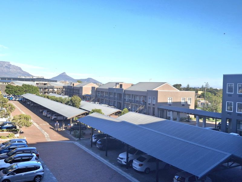 Elevated view of the office complex parking area featuring covered parking bays and paved driveways with mountain views in the background.