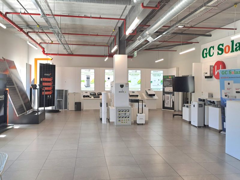 Spacious industrial showroom featuring exposed ceiling infrastructure, tiled flooring, and integrated lighting, currently utilized for solar energy product displays.