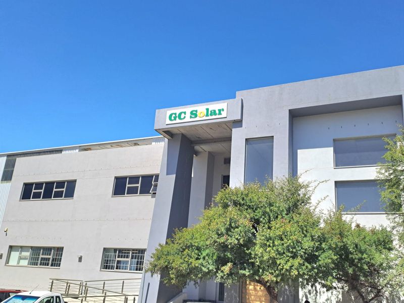 Front elevation of an industrial building featuring a prominent entrance, grey facade, and large windows, suitable for commercial or warehouse operations.