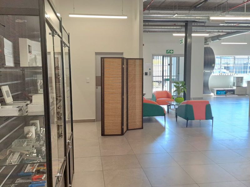 Spacious industrial office or showroom area featuring high exposed ceilings, tiled flooring, and integrated fire safety systems.