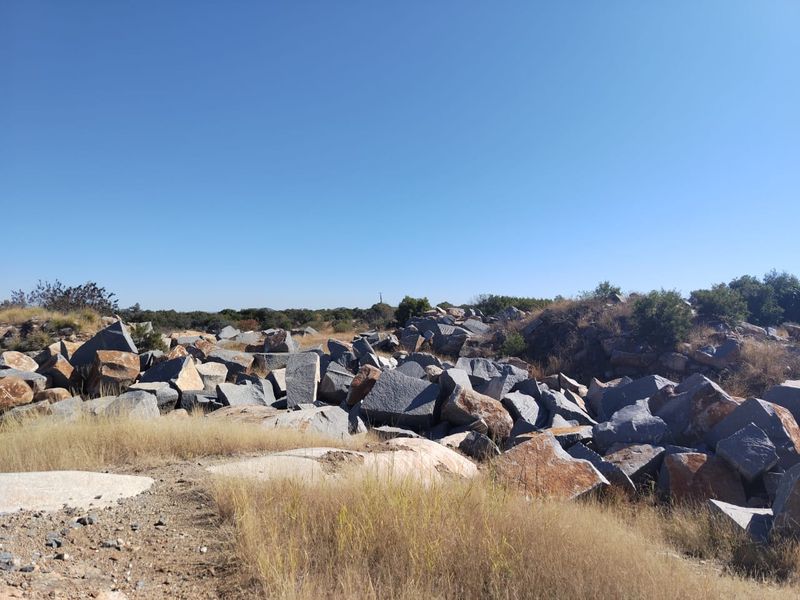 An expansive outdoor area on the farm featuring natural rock formations and dry, open landscape under a clear blue sky.
