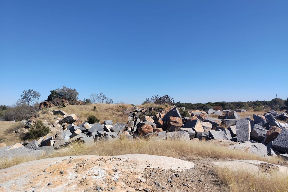 A wide-angle view of the natural landscape featuring rocky outcrops and native dry grass typical of the farm property.