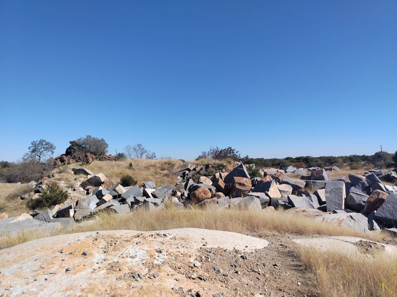 A wide-angle view of the natural landscape featuring rocky outcrops and native dry grass typical of the farm property.
