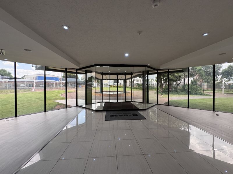 Spacious modern entrance lobby featuring extensive floor-to-ceiling glass walls providing panoramic views of the surrounding landscaped grounds.