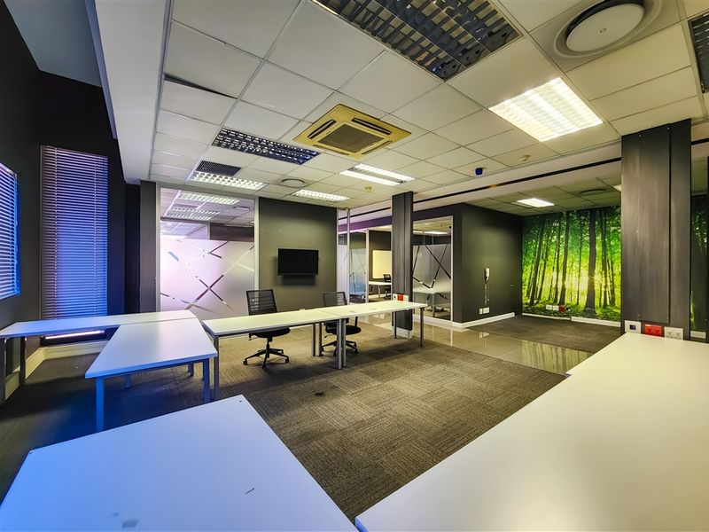 Modern open-plan office space featuring suspended acoustic ceiling tiles, recessed lighting, integrated air conditioning, and glass partitioning for a professional work environment.