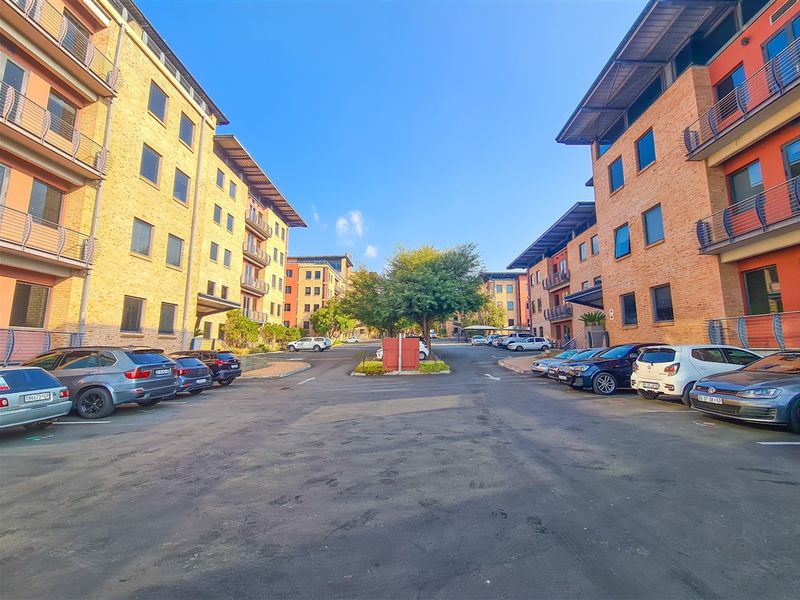 Exterior view of a modern office park complex featuring multi-story brick buildings with metal roofing and paved parking areas.
