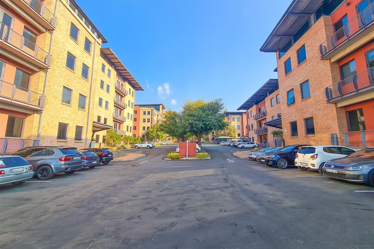 Exterior view of a modern office park complex featuring multi-story brick buildings with metal roofing and paved parking areas.