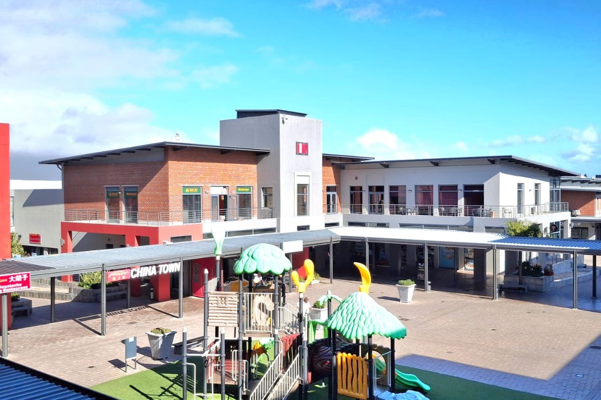 An elevated view of a commercial office complex courtyard featuring paved walkways, covered corridors, and a central playground area.