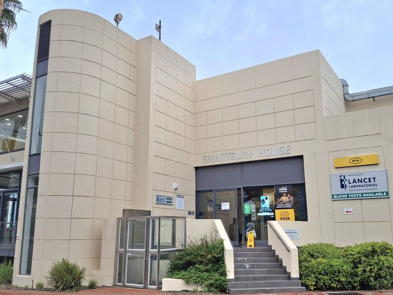 Front facade of Smartsury House office building featuring a prominent curved architectural element, glass entrance, and external signage for commercial tenants.