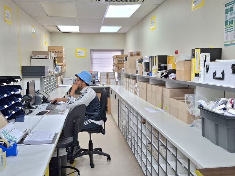 A functional office workspace featuring extensive built-in shelving, grid storage units, and integrated ceiling air conditioning.