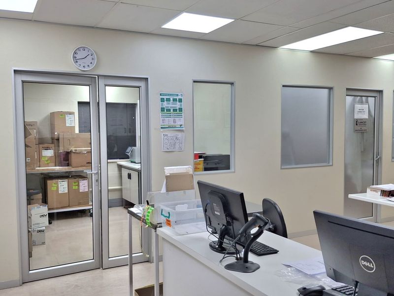 A functional office space featuring glass partition walls, suspended ceiling with recessed lighting, and durable vinyl flooring, suitable for professional or clinical use.