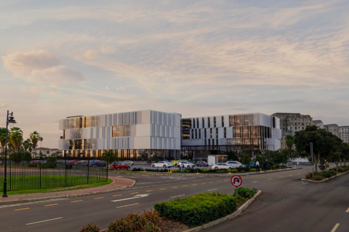 A modern multi-story office building featuring a contemporary glass and panel facade with an adjacent parking area and landscaped surroundings.