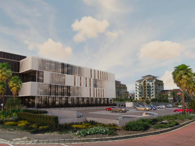 A modern multi-story office building featuring a contemporary facade with glass curtain walls and vertical louvers, complemented by a paved parking area and landscaping.