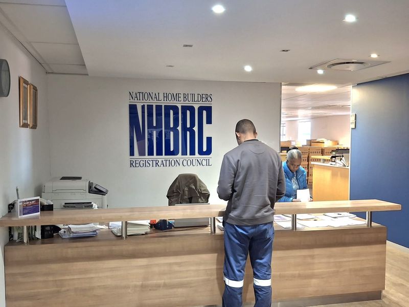 Professional office reception area featuring a built-in wooden service counter, recessed lighting, and clean laminate flooring.