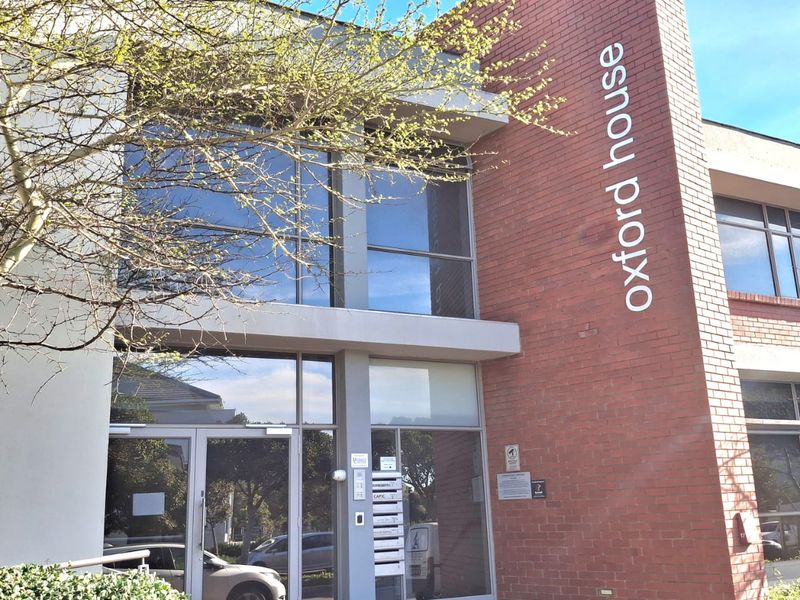 Front exterior view of Oxford House, featuring a modern brick and glass facade with a prominent entrance and professional signage.