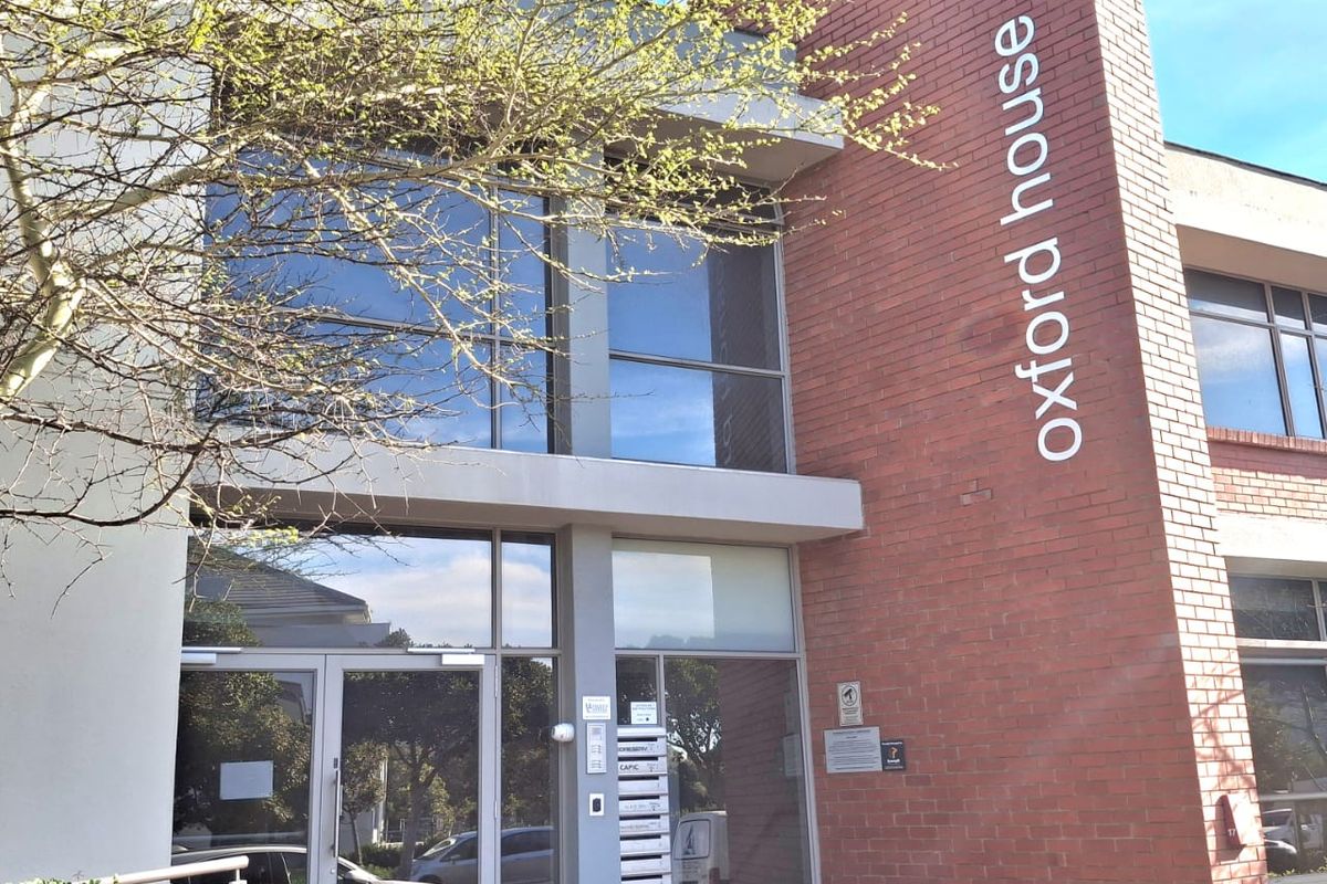 Front exterior view of Oxford House, featuring a modern brick and glass facade with a prominent entrance and professional signage.