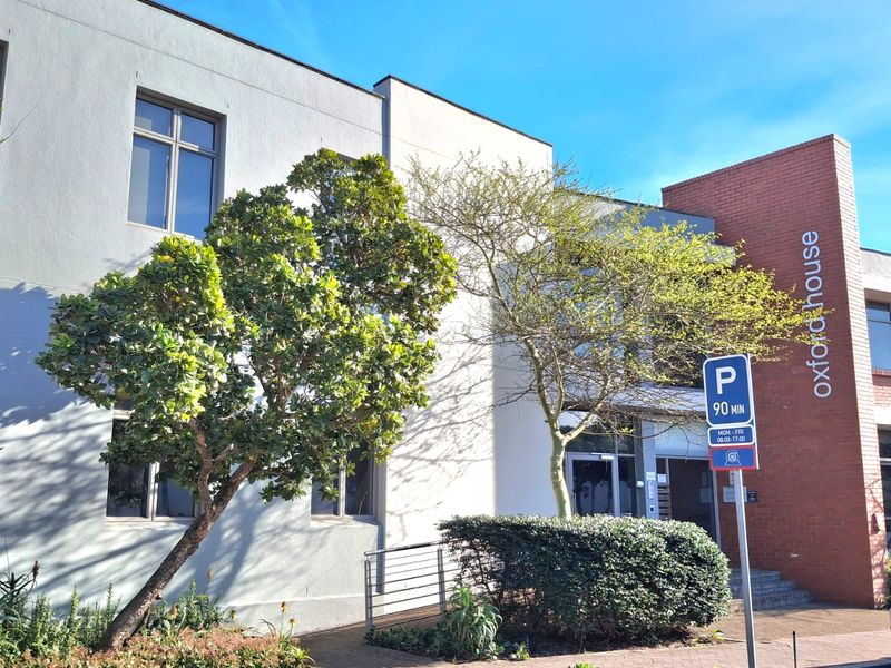 Front exterior view of Oxford House, featuring a modern combination of plastered and brick facade with a paved entrance and landscaped garden area.