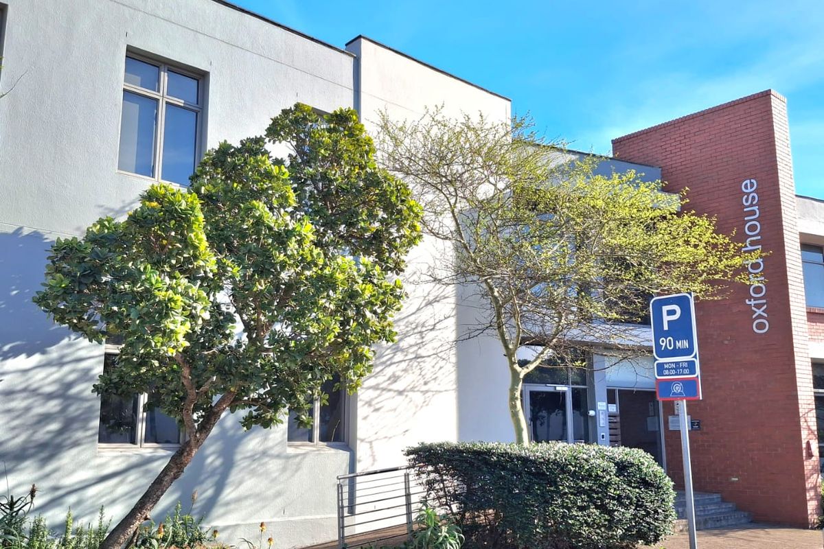 Front exterior view of Oxford House, featuring a modern combination of plastered and brick facade with a paved entrance and landscaped garden area.