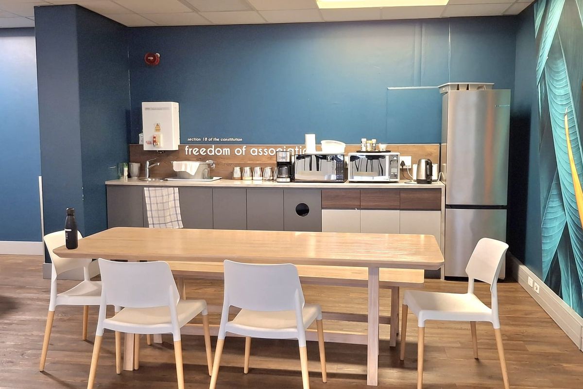 A functional office kitchenette featuring built-in cabinetry, a sink, and wood-look laminate flooring, providing a convenient break area for staff.